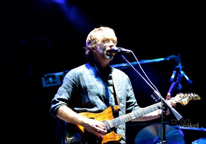 Musician playing guitar and singing on stage.