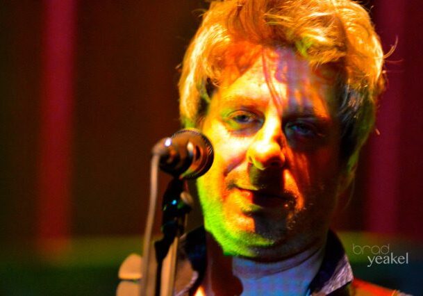 Musician singing on stage with microphone.