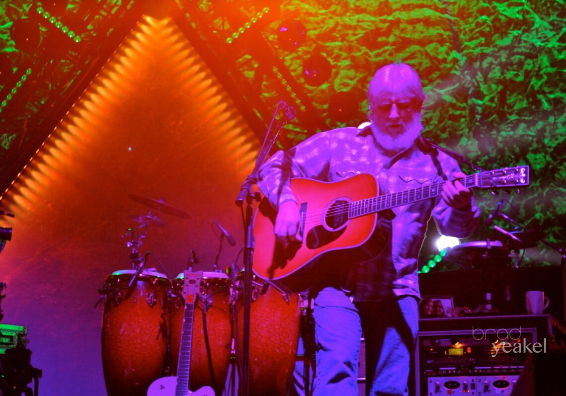 Musician playing guitar on colorful stage.