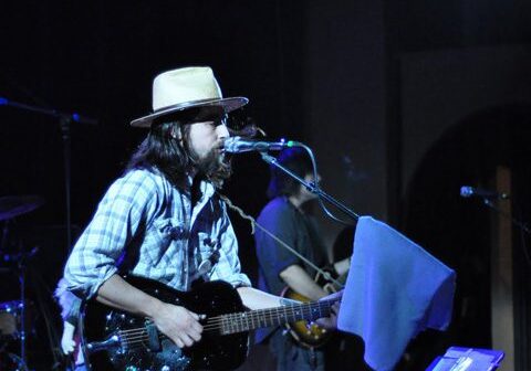 Musician performing on stage with guitar.
