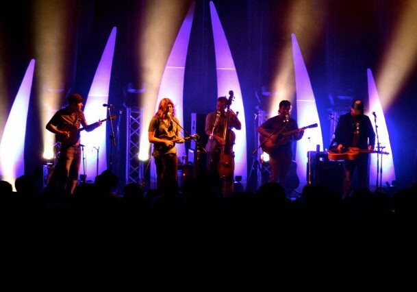 Band performing on stage with colorful lights.