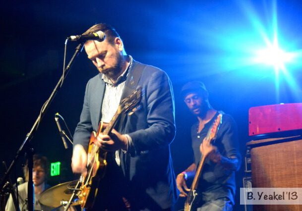 Musicians performing on stage with bright lights.