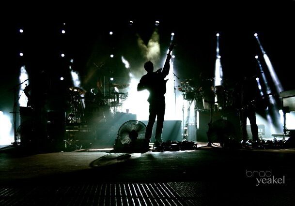 Silhouetted band performing on a dimly lit stage.