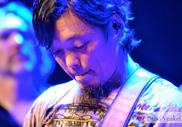 Guitarist performing under blue stage lights.