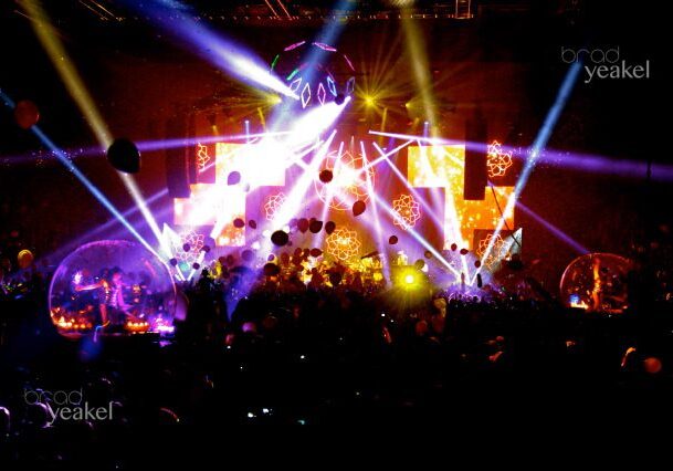Concert stage with vibrant lights and balloons.