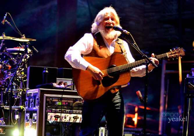 Musician performing on stage with guitar.