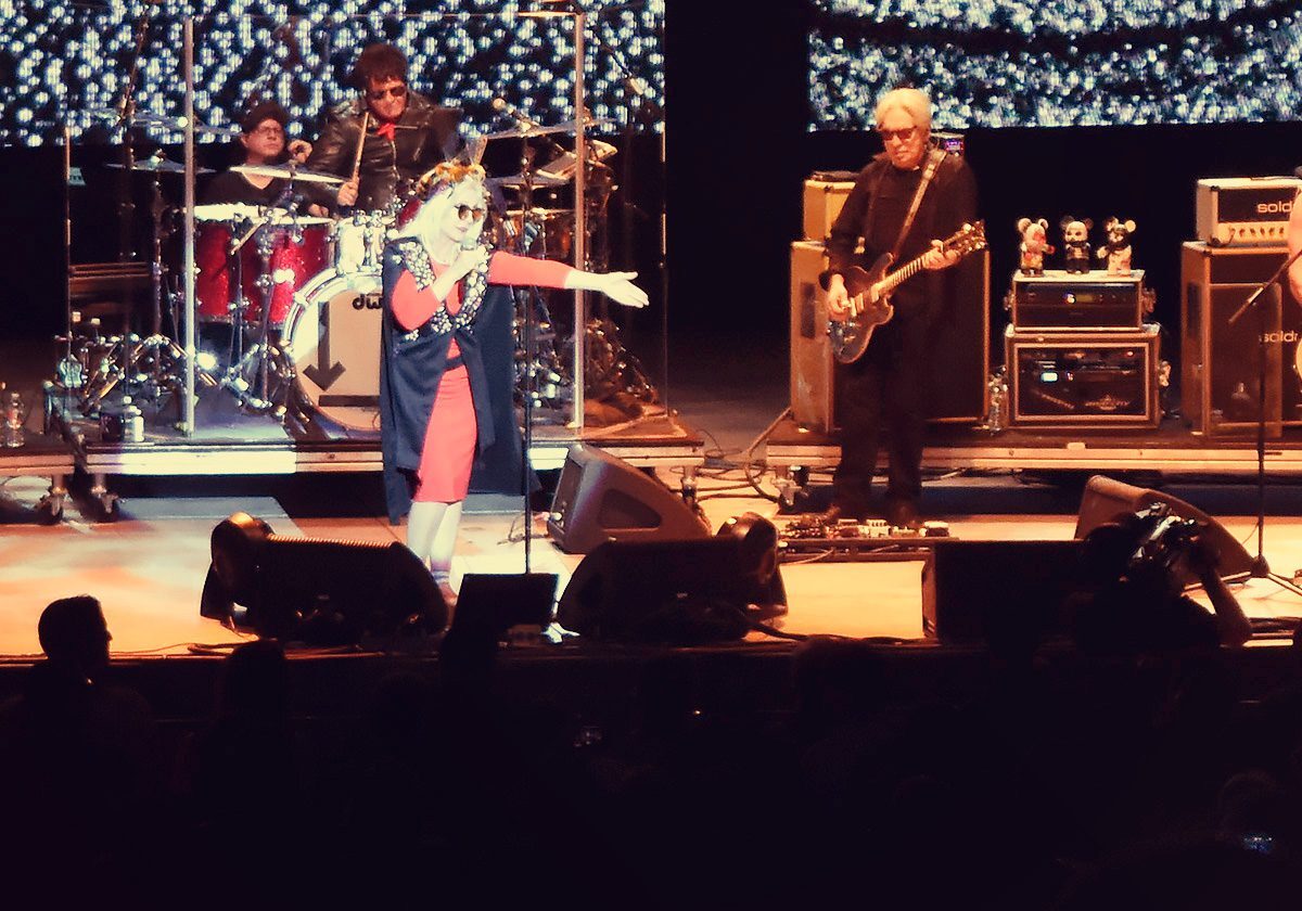 Band performing live on stage with instruments.