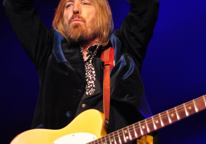 Musician performing with electric guitar on stage.