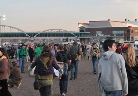 Outdoor crowd near a large event center.