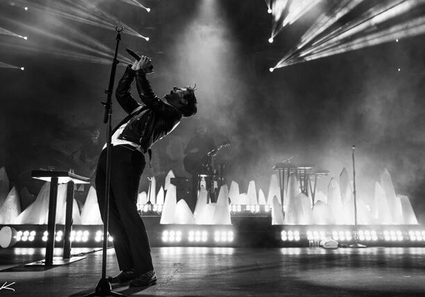 Singer performing on stage with dramatic lighting.
