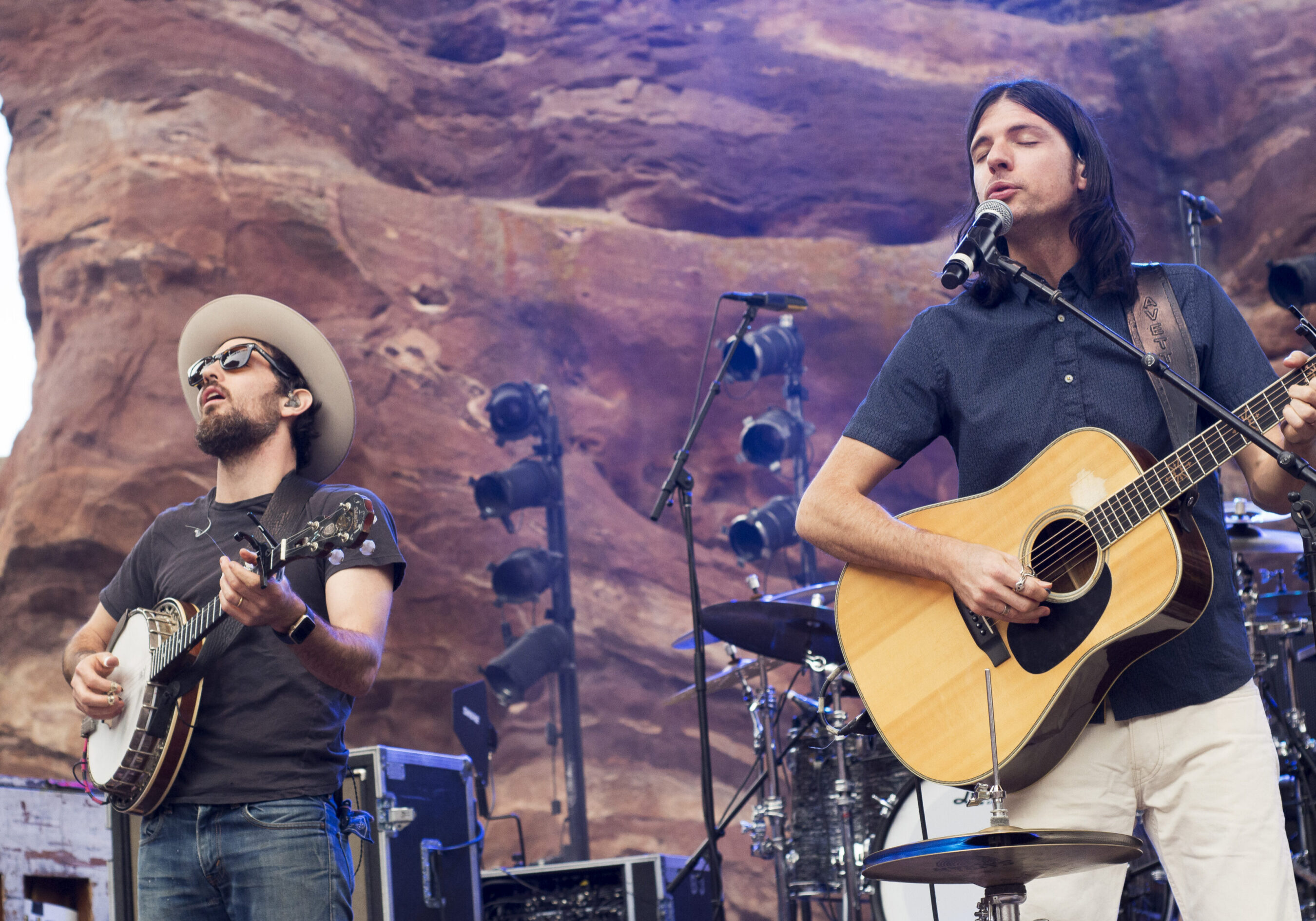 Musicians performing with guitars on outdoor stage.