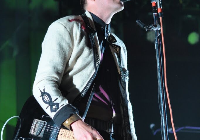Musician performing on stage with guitar.