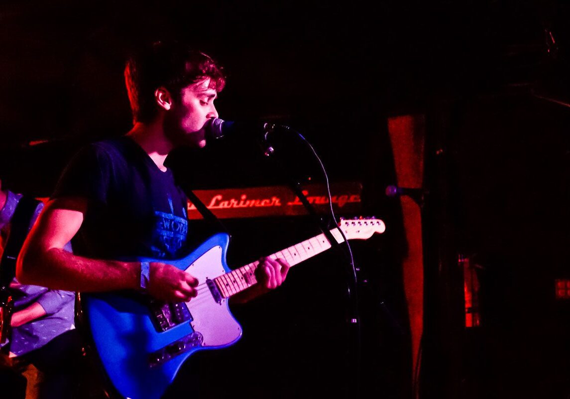 Musician playing electric guitar on stage.