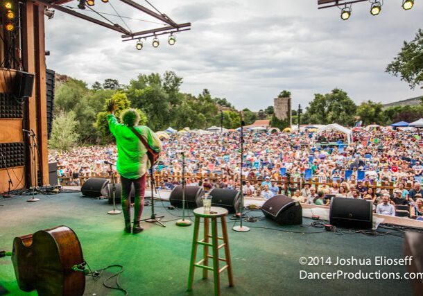 Musician performing on stage before large crowd.