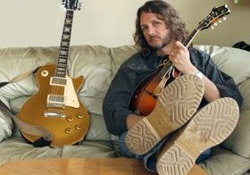 Man with mandolin, guitar on couch.