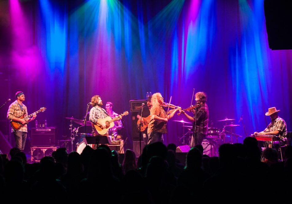 Band performing on stage with colorful lights.