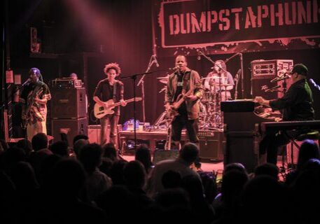 Band performing live on stage with instruments.
