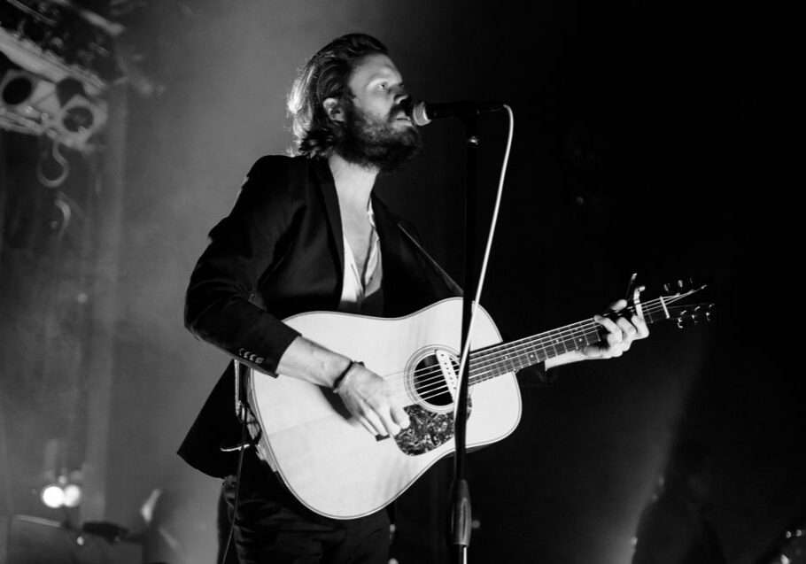 Musician performing on stage with guitar.