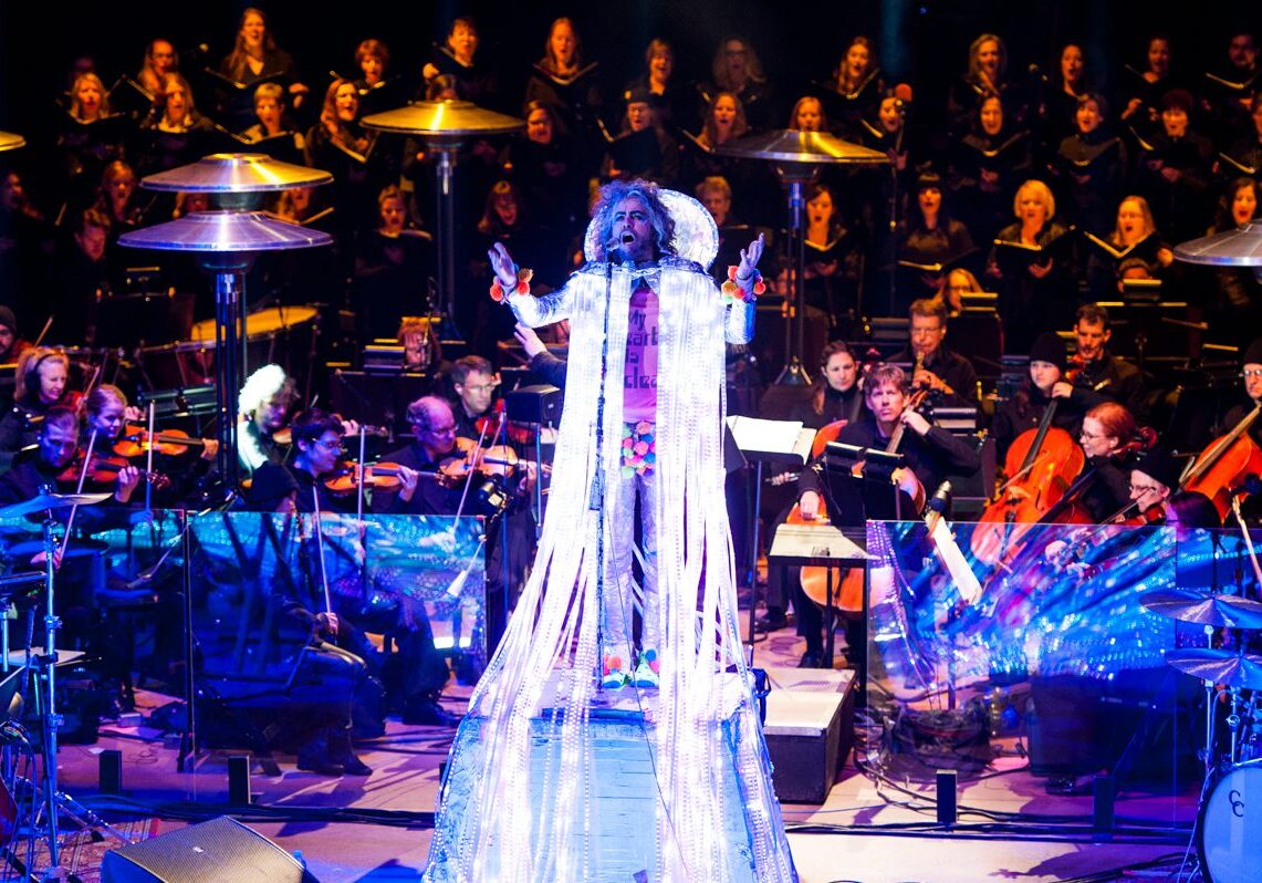 Performer onstage with orchestra and choir ensemble.