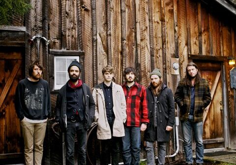 Six people standing in front of cabin.