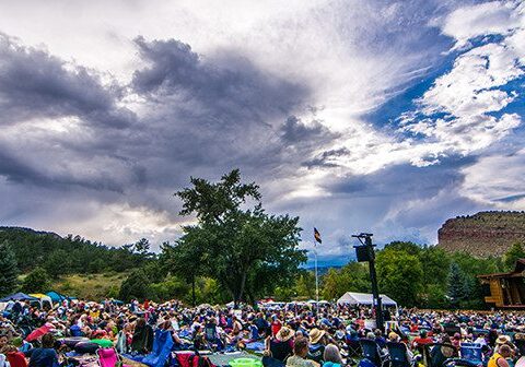 Outdoor festival crowd under dramatic cloudy sky.