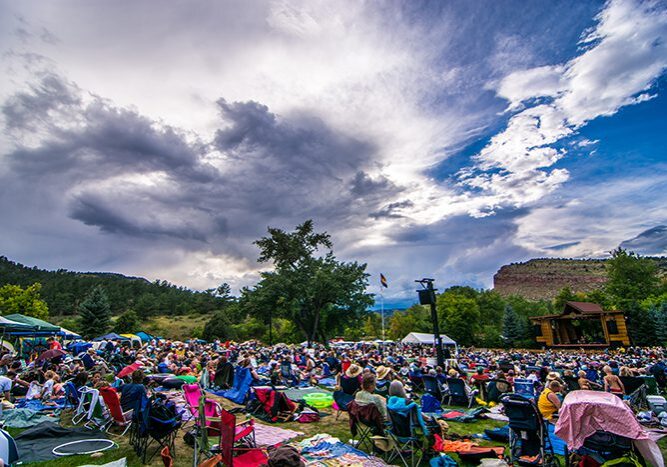 Outdoor festival crowd under dramatic cloudy sky.