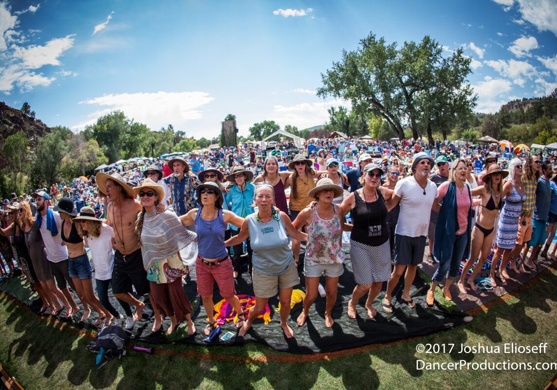 Crowd at outdoor festival, standing together.