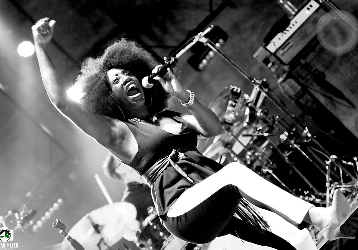 Singer performing energetically on stage, monochrome image.