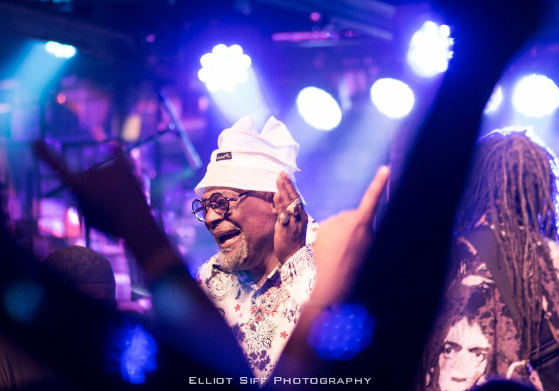 Musician performing on stage with bright lights.