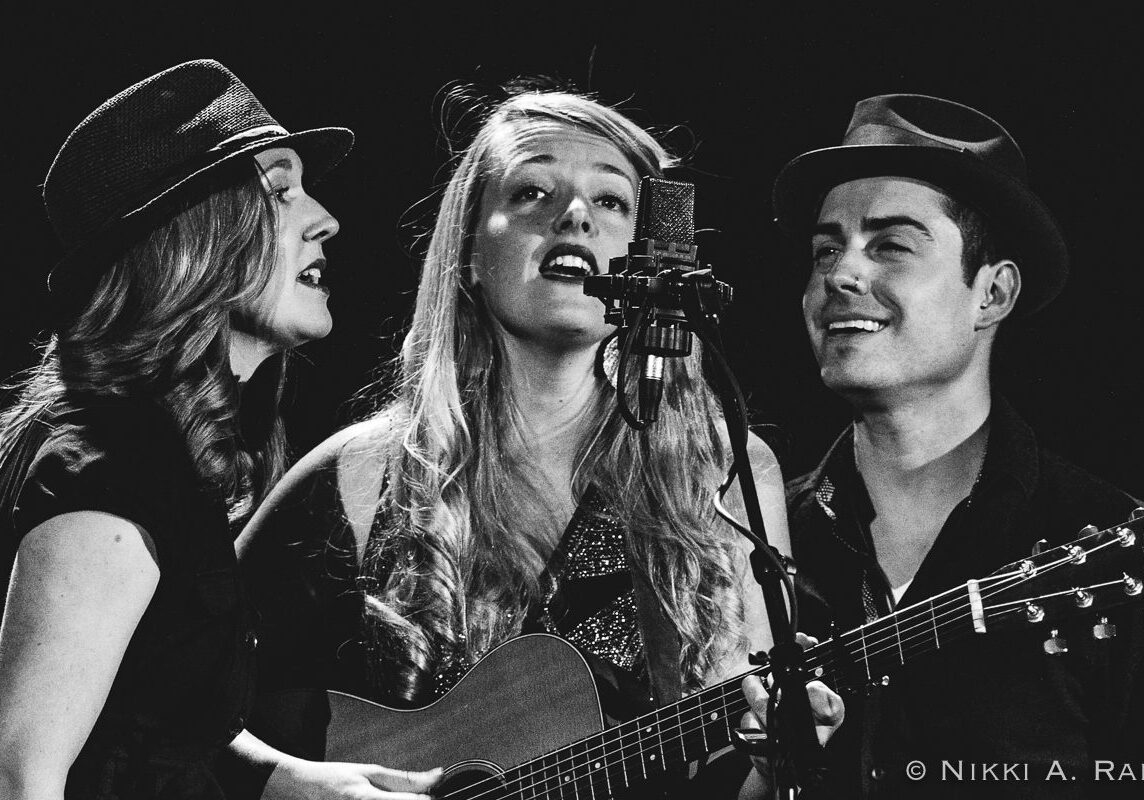 Trio singing with guitar and microphone.