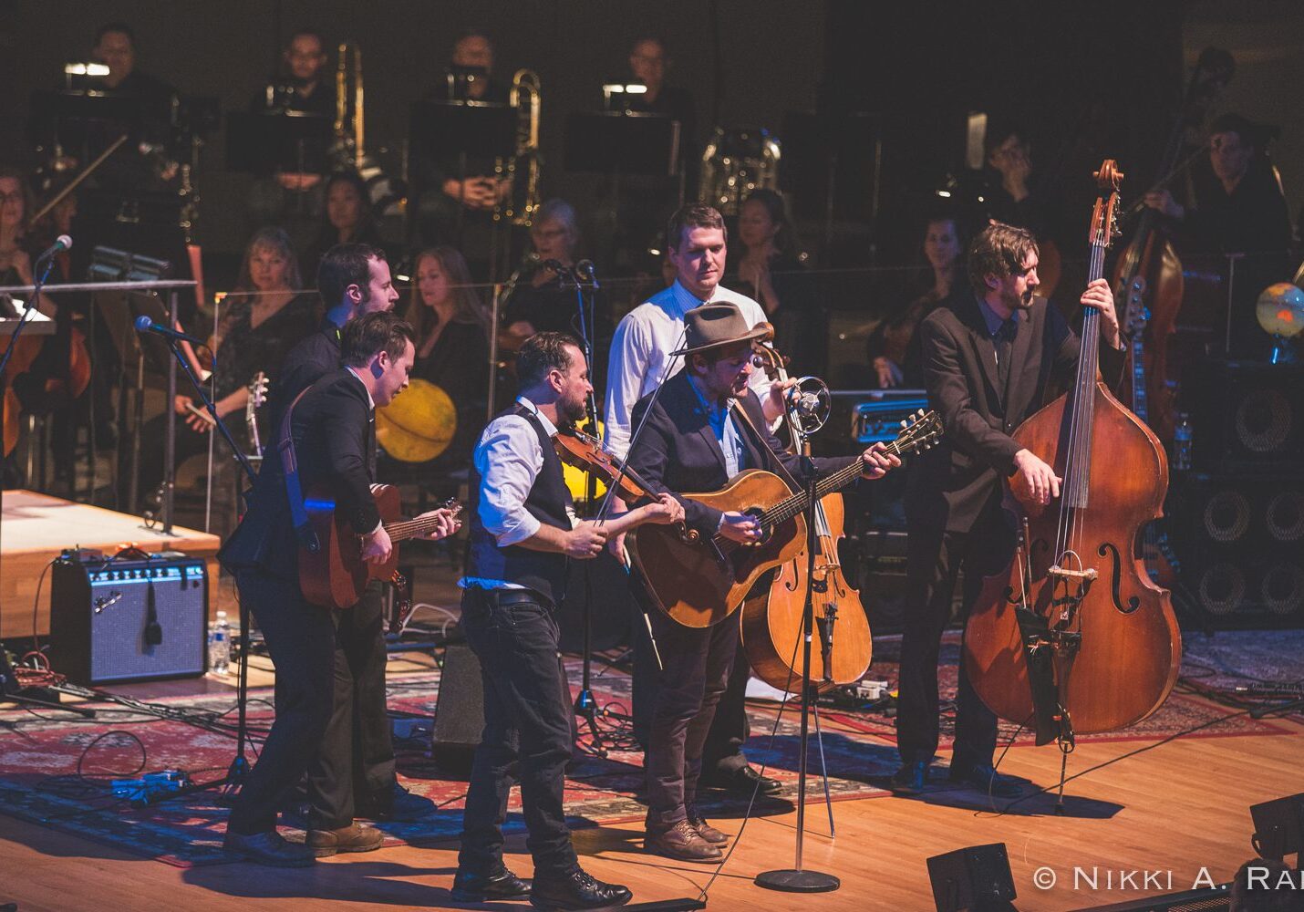 Band performing on stage with orchestra behind.