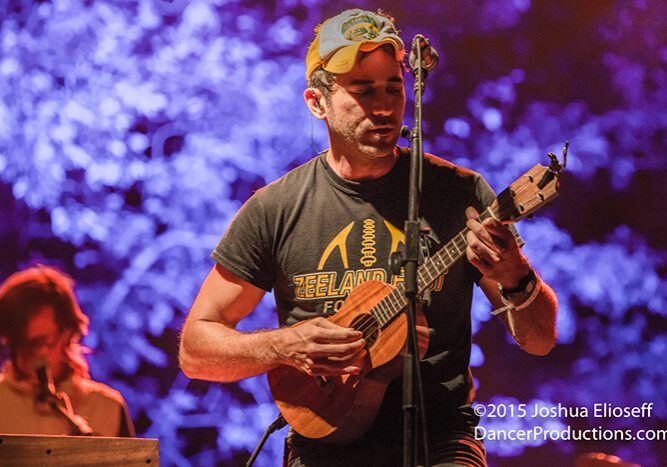 Musician playing guitar on vibrant stage.
