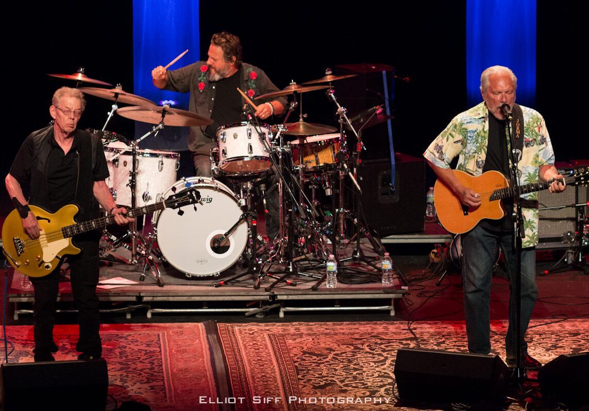 Three musicians performing live on stage.