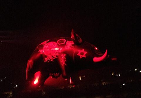 Red inflatable pig with various symbols.