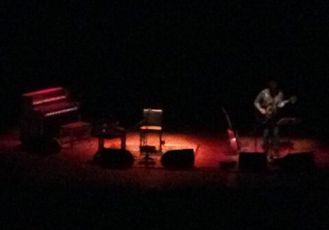Dimly lit stage with musician and instruments.