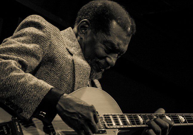 Man playing guitar intensely on stage.