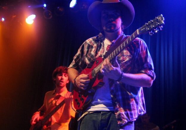 Musicians performing on stage with guitars.