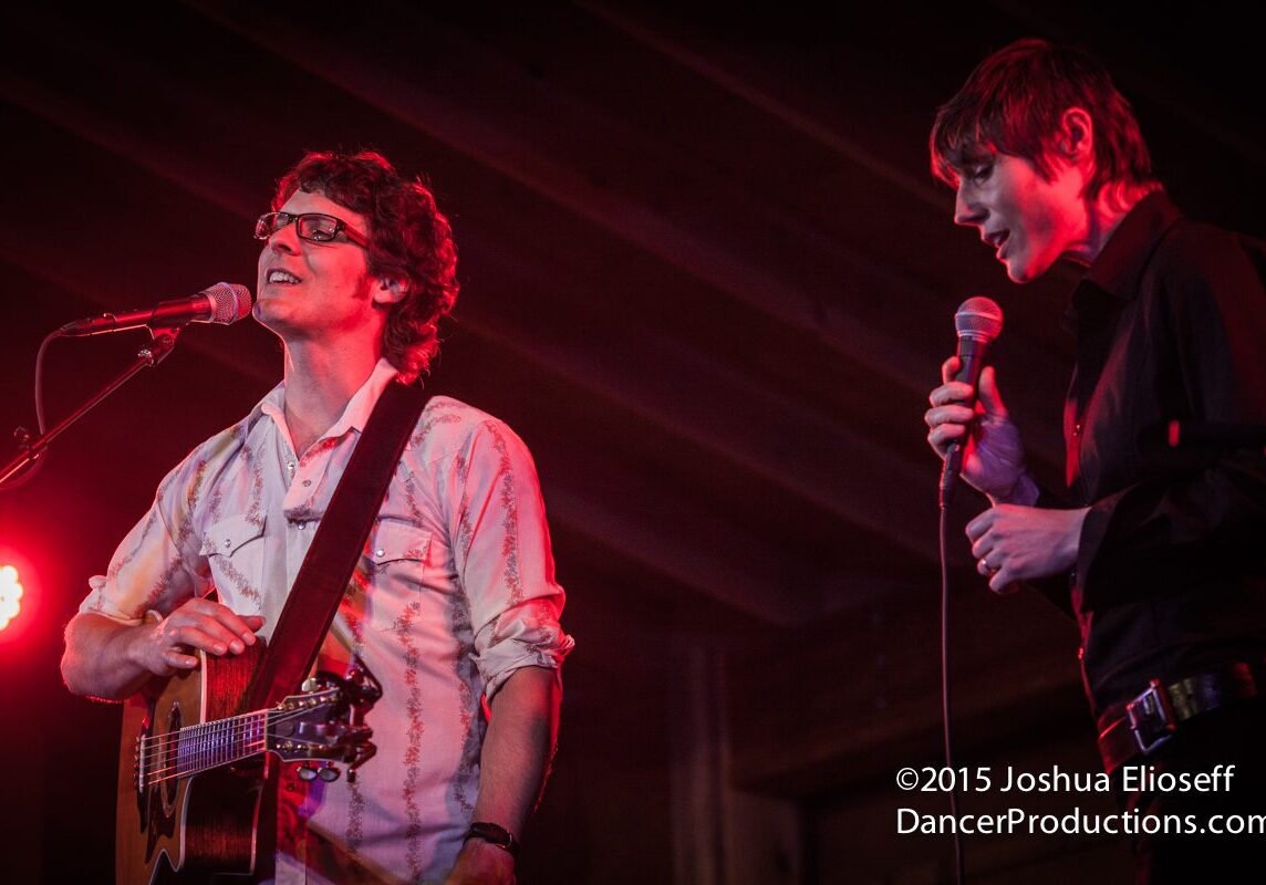 Two musicians performing on stage with microphones.