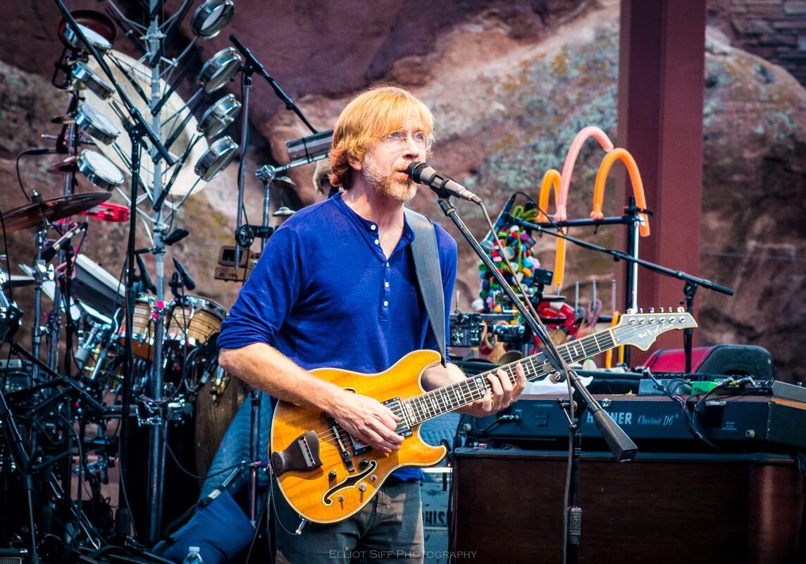 Musician performing with guitar on stage.