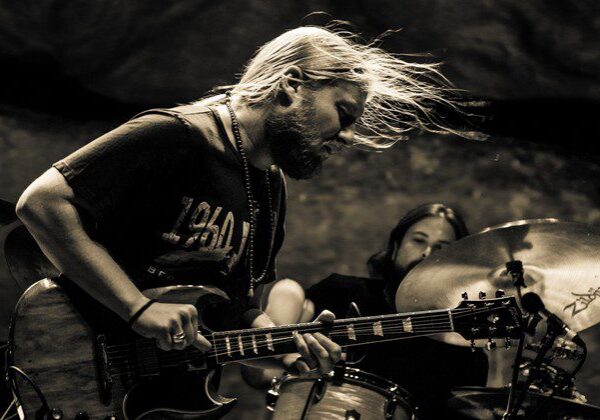 Guitarist and drummer performing intensely on stage.