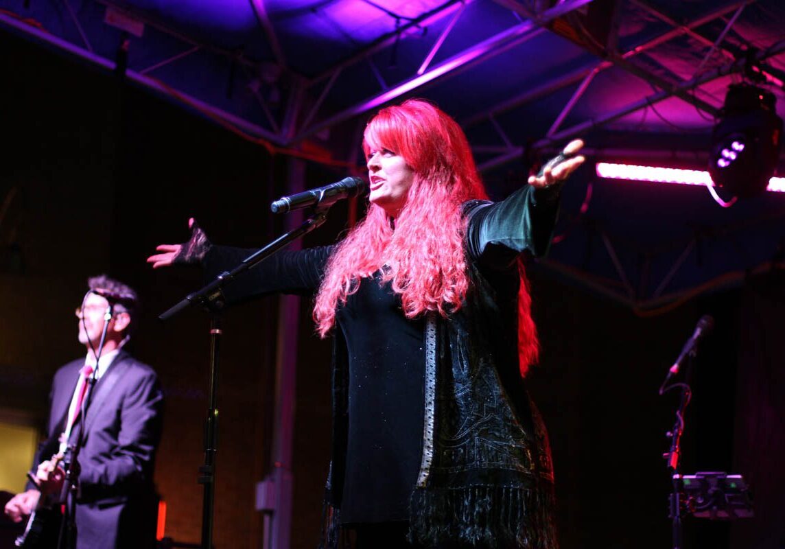 Singer performing on stage with guitarist.