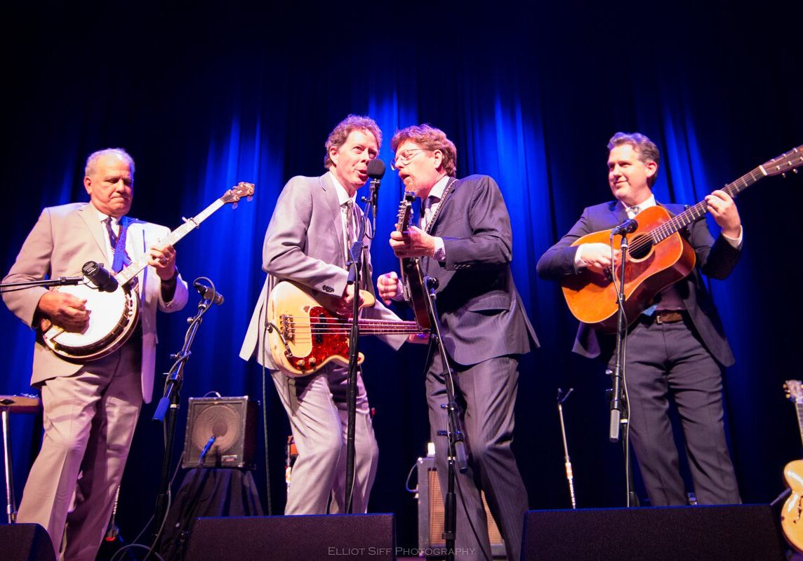 Band performing live on stage with instruments.
