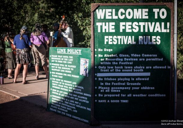 Festival rules sign with people in background.