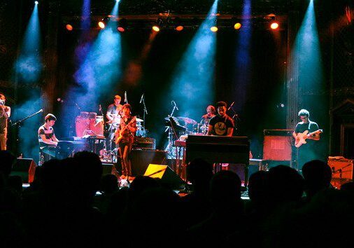 Live band performing on stage with lights.
