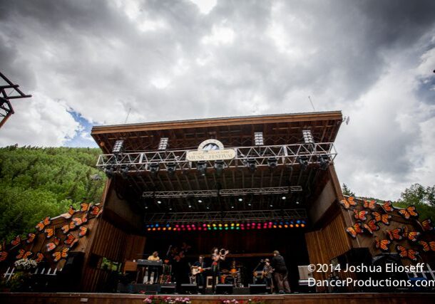 Outdoor concert stage with cloudy sky backdrop.