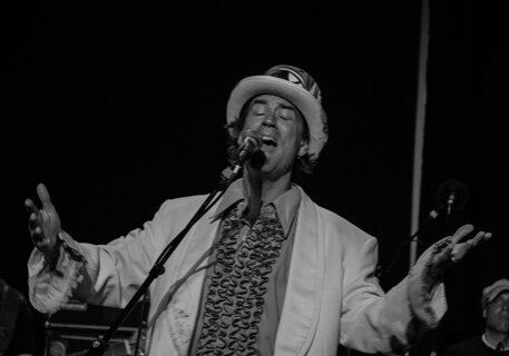 Singer performing passionately on stage in monochrome.