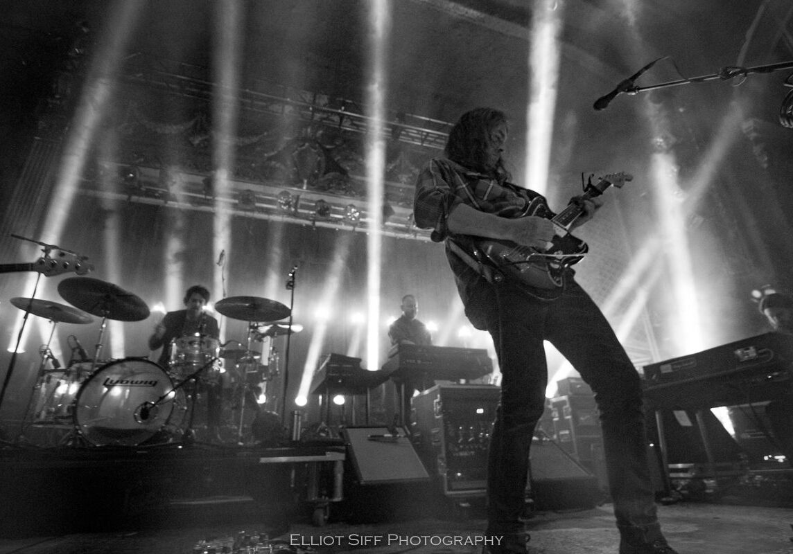 Band performing live with dramatic lighting effects.