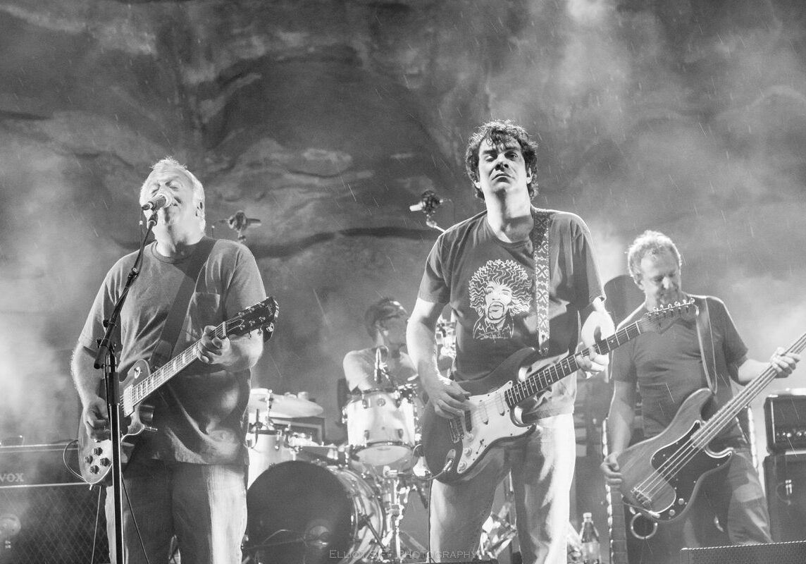 Rock band performing on stage with guitars.