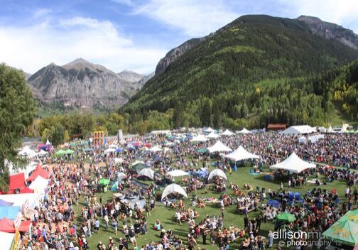 Outdoor festival with tents and mountain backdrop.