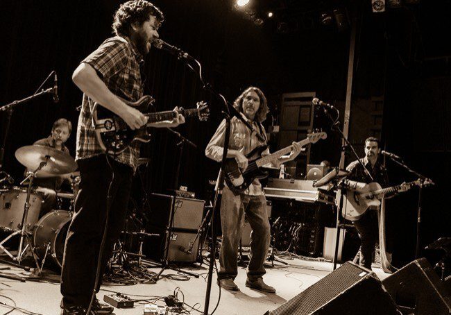 Band performing live on stage in sepia.